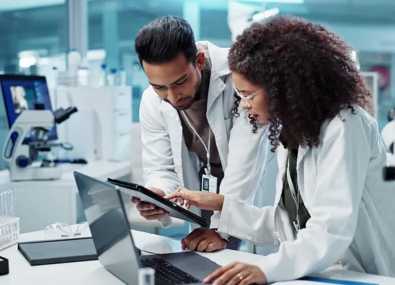 Equipe de laboratório analisa resultados em tablet e notebook