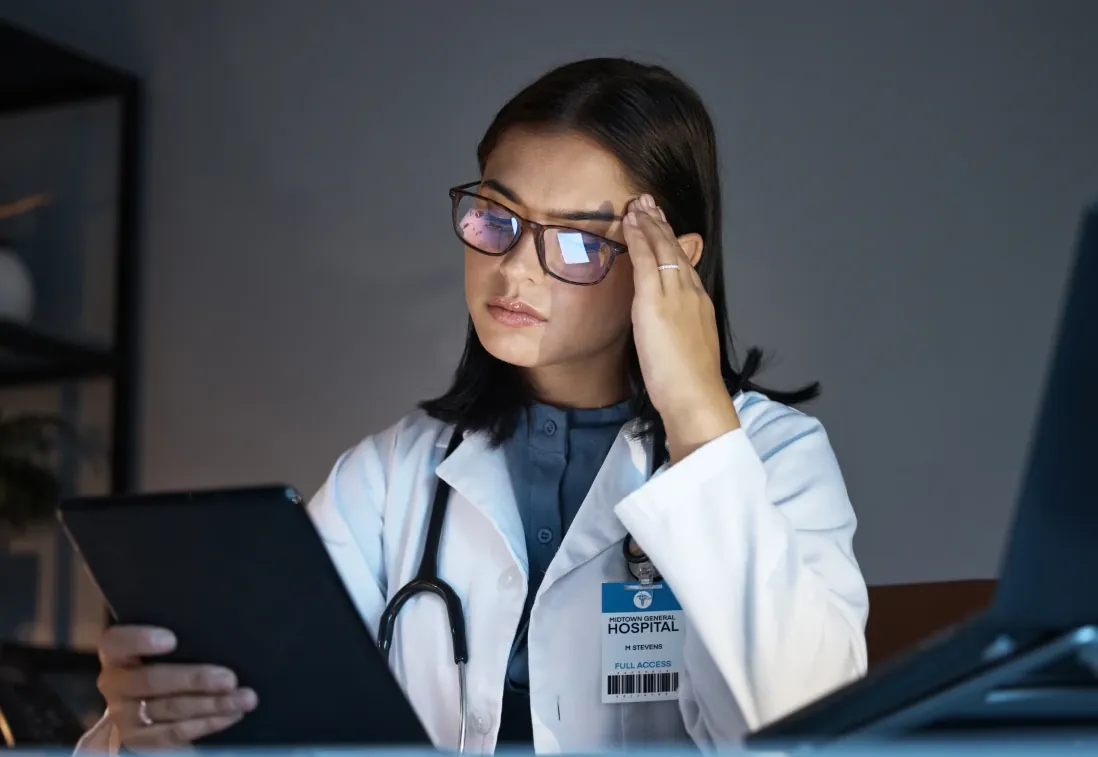 Médica olha para o tablet com expressão de cansaço